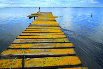 Fototapeta premium Photographie de Michel Rauscher femme assise sur un ponton jaune à l'Etang de Thau dans l'Hérault en France