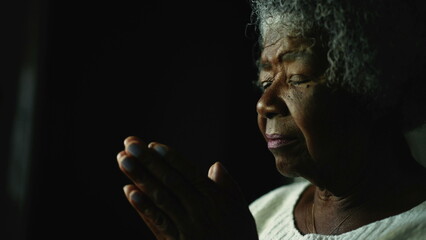 A spiritual older woman praying to God a senior African person prays