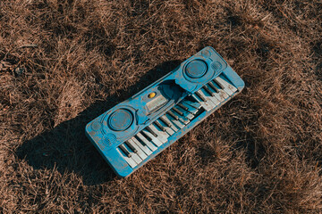 Old destroyed toy synthesizer on the ground. Broken abandoned musical synth for kids