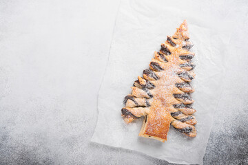 Puff pastry Christmas tree with chocolate paste, sprinkled with powdered sugar on a gray background. Christmas or Xmas pastries. Top view. Copy Space