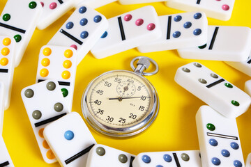 Stopwatch and scattered dominoes on a yellow background. Times up.
