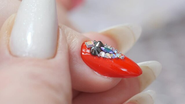 Laying out a pattern of rhinestones on the nail with a spatula and a thin brush.