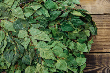 A dry birch broom lies on a wooden background. Accessories for baths and saunas.