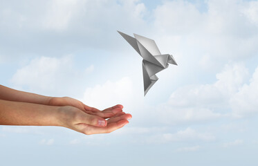 Concept of hope and freedom as human hands release a magical flying  origami bird made of paper as...
