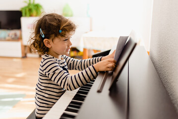 Girl piano student places a sheet of music on her piano to practice