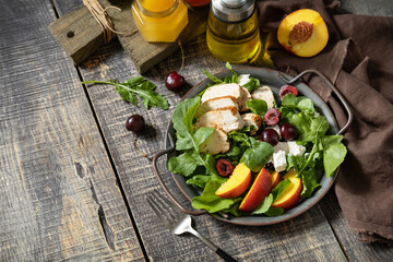 Healthy diet salad with grilled turkey, arugula, peach, cherry, feta and vinaigrette dressing on a...