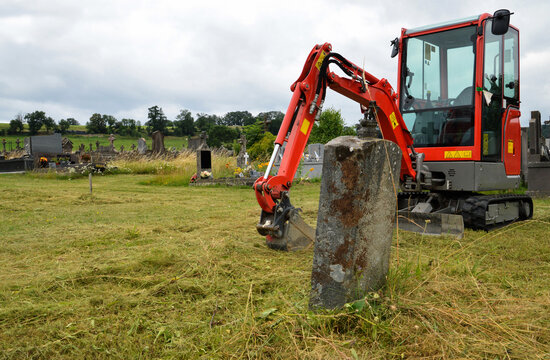 An excavator for digging a grave in a cemetery for burial or exhumation.