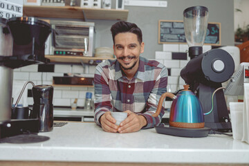 Portrait of man barista standing behind the bar counter with cup