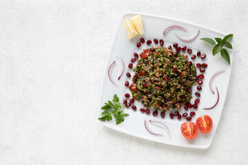 Traditional Tabbouleh salad with parsley on white table. Table top view.