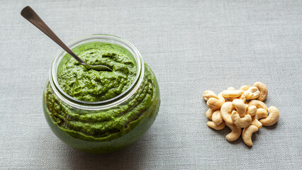 Bowl jar with green chutney sauce dip from leaves with cashew nuts.