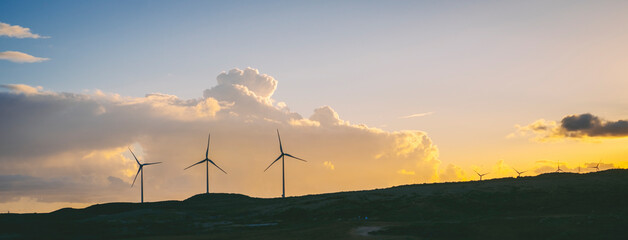 Wind turbines in the country side against a blue sky with clouds background. Concept of green energy production and good future environment lifestyle. Renewable electricity farm with wind mills © simona