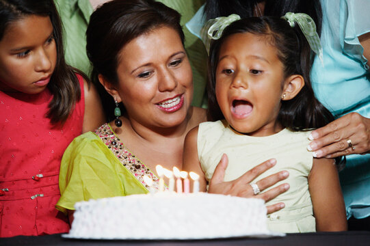 Young girl blowing out the candles on her birthday cake