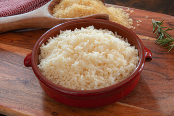 raw and cooked rice in bowl on wooden background