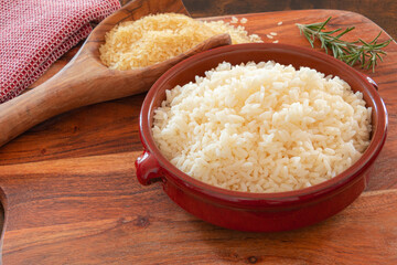 raw and cooked rice in bowl on wooden background