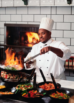 Male chef cooking food near fireplace