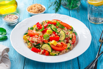 Vegetarian salad with avocado and quinoa and fresh herbs on a blue background.
