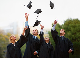 Heres to the rest of our lives. A group of students throwing their caps into the air after graduation.