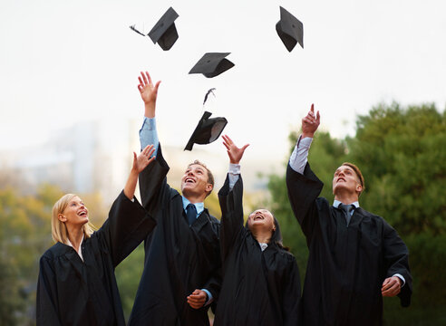 Heres to the rest of our lives. A group of students throwing their caps into the air after graduation.