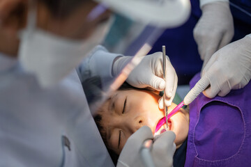 Obraz na płótnie Canvas Hand of Doctor dentist is working on the teeth of asian little kid 6 year old patient in dental clinic