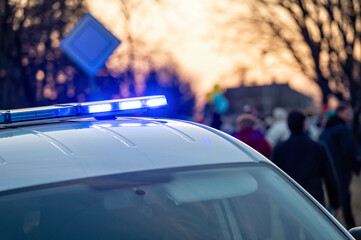 municipal police car with beacons on instead of "Stand With Ukraine" rally, evening lights