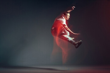 Fototapeta na wymiar Dancing energetic jumping sporty girl in motion, dance freestyle. Breakdancer in red neon studio light. Long exposure