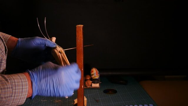 puppet master makes a wooden grasshopper doll