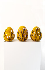 Orange crocheted Easter eggs on a white background with copy space, front view banner