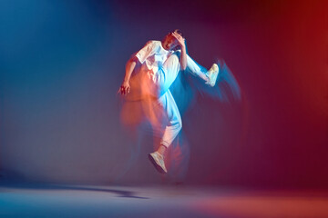 Obraz na płótnie Canvas Dancing energetic girl jump, moving in hip-hop dance in colourful neon light. Long exposure. Breakdancing school ad