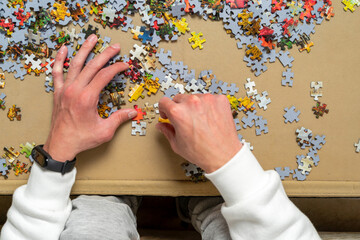 Hand of a young boy trying to solve a puzzle, he is putting together the small pieces in various sectors. entertainment concept.