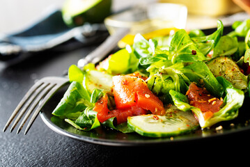 Fresh salad with avocado, cucumber, salmon. Dressing with honey, dijon mustard, olive oil and lemon juice