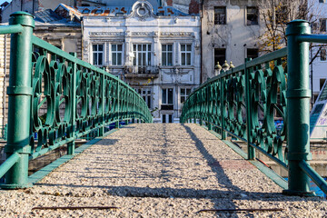 Old green metallic rusted bridge over Dambovita river in Bucharest, Romania, in a sunny autumn day. - obrazy, fototapety, plakaty