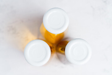 Top view on caps of glass bottles with yellow and red liquid healthy beverage on gray background