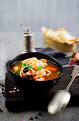 Pan Asian traditional seafood soup with mussels, calamari, mushrooms served with fresh parsley herbs