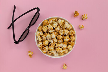 caramel popcorn and 3D glasses on pink background