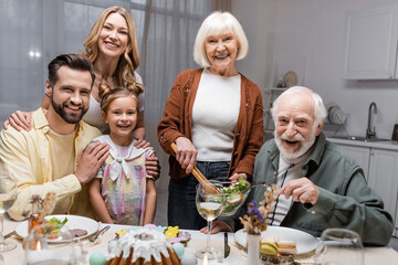 joyful family looking at camera near table served with festive easter dinner.