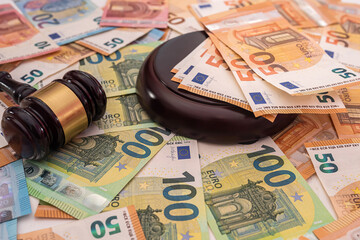 on the beautiful brand new euro bills lies a strong wooden gavel of the judge