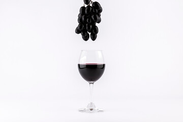 Red wine in glasses with grapes on white background.