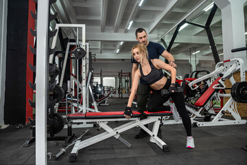 beautiful woman doing intense sports in the gym with a young beautiful trainer.