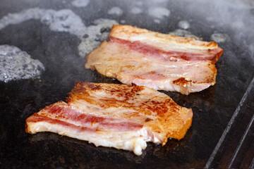 Grilled crispy smoked bacon on barbecue. Fast food, bbq, grill.