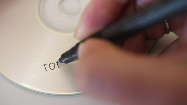 woman hand writing words top secret on blank cd rom, detail static closeup