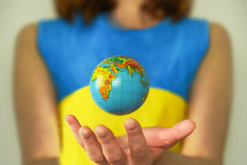 Earth and flag of Ukraine. Woman with globe. Concept of impact of war on world
