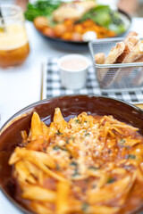 Pasta, salad and grilled halumi cheese in a metal basket, colorful cocktails in the background