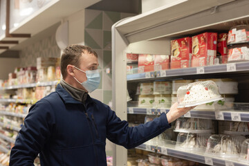 A Man Buying Groceries In A Supermarket, Wearing A Protective Face Mask. A Person Buying Food During An Outbreak Of The Coronavirus Pandemic. Food and drinks