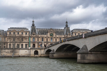 Obraz premium The Seine under a bridge in Paris, France, with the Louvre in the distance