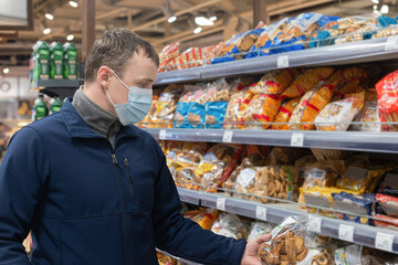 A Person Buying Food During The Outbreak Of The Coronavirus Pandemic. A Man Buying Groceries In A Supermarket, Wearing A Protective Face Mask. Food and drinks
