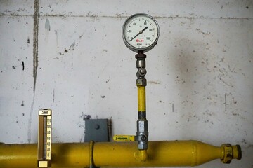 Gelbes Filterrohr mit Thermometer vor alter weißer Betonwand 
