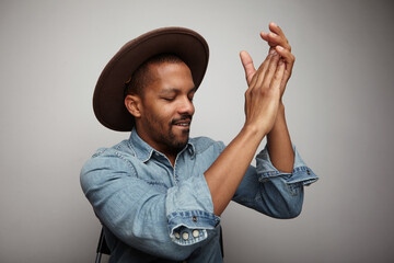 Young handsome man wearing hat clapping hands and dancing on white background.