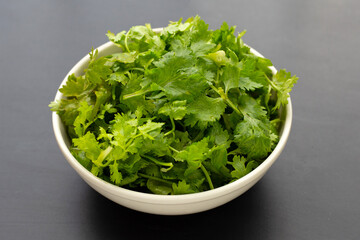 Coriander in white bowl on dark background.