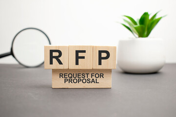 The words RFP Request for Proposal is written on wooden cubes between a pen and a calculator on a light background.