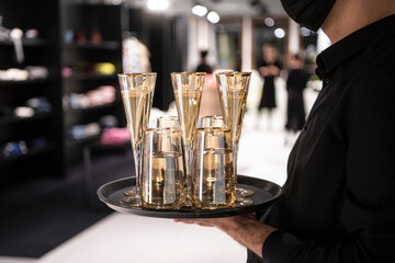 A professional waiter holding sparkling champagne wine glasses served on a tray. Catering service. Concept of welcoming people at an event and luxury party.